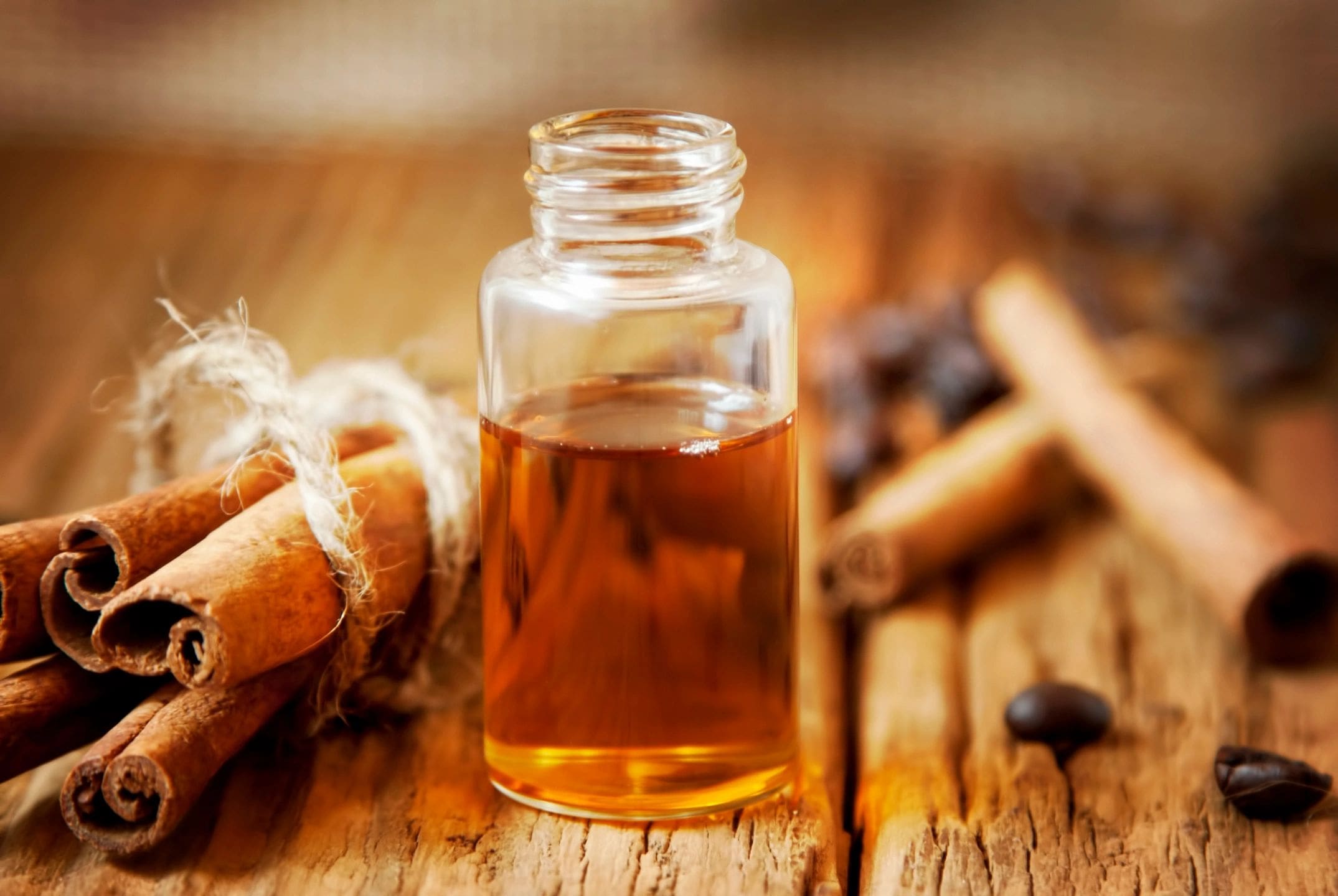 A glass bottle filled with amber liquid on a wooden surface.