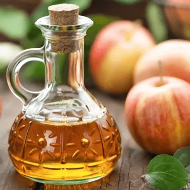 Glass jar of apple cider vinegar with apples.